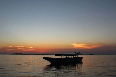 Silhouette boat in sea against sky during sunset