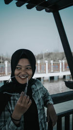 Portrait of smiling young woman standing against built structure