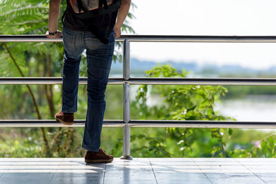 Low section of man standing on railing