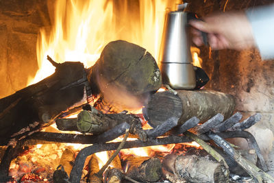 Cropped hand preparing food on campfire