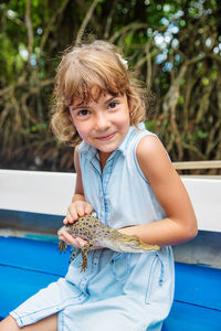 Portrait of girl holding alligator