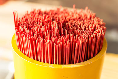 Close-up of red incense sticks in yellow container