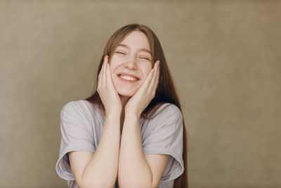 Portrait of young woman standing against yellow wall