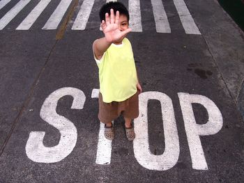 Full length of boy showing stop gesture while standing on road