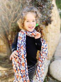 Portrait of young woman standing against trees