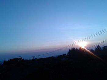 Low angle view of silhouette cables against sky during sunset