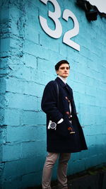 Portrait of young man standing against building