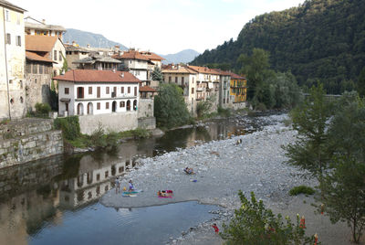 Houses by river against sky