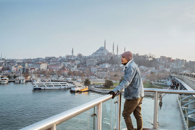 Rear view of man standing on bridge against clear sky