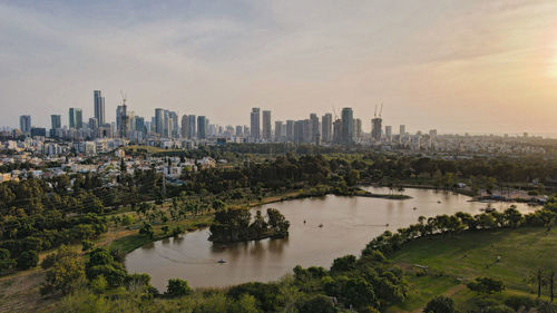 Aerial view of buildings in city against cloudy sky