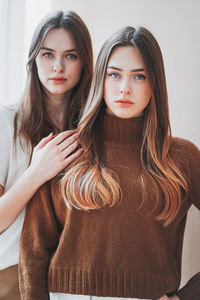 Portrait of beautiful females standing against beige background