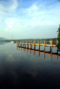 Wooden pier in lake against sky