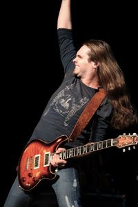 Young man playing guitar against black background