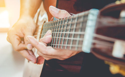 Midsection of man playing guitar