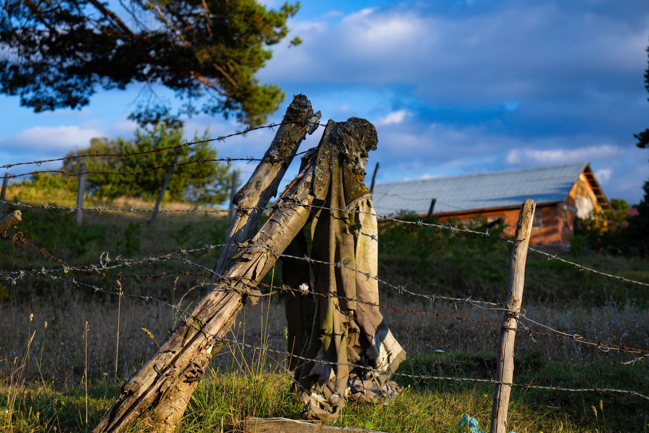 WOODEN POST ON FIELD AGAINST SKY