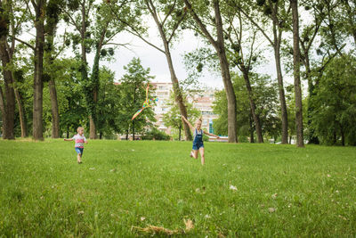 Full length of children running while flying kite on field