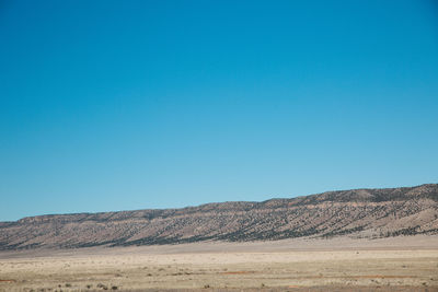 Scenic view of desert against clear blue sky
