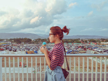 Woman standing on railing against cityscape