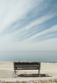 Bench by sea against sky