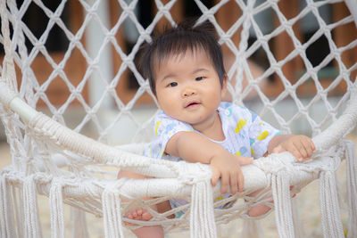 Portrait of cute baby girl behind fence