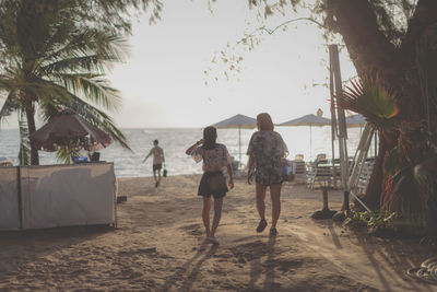 Rear view of people on beach against sky