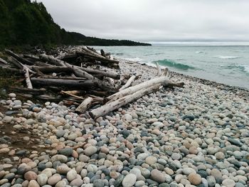 Pebbles on beach against cloudy sky