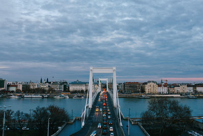 View of suspension bridge over river against cloudy sky