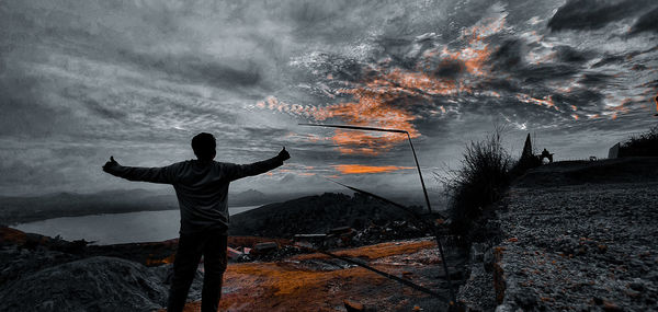 Rear view of man standing against sky during sunset