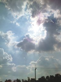 Low angle view of electricity pylon against cloudy sky