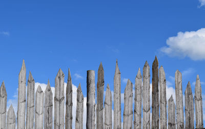 Low angle view of fence against blue sky