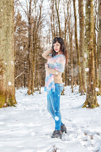 Full length of smiling woman standing on snow covered land