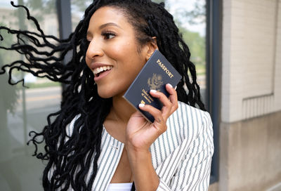 Portrait of a smiling young woman holding passport