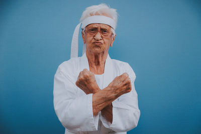 Portrait of senior woman doing karate against blue background