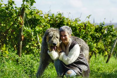 Portrait of mature woman with dog on grassy field