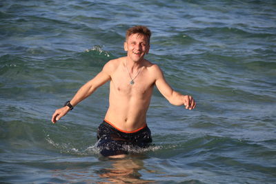 Portrait of shirtless man walking in sea