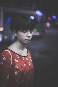 Portrait of young woman in city at night