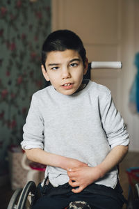 Portrait of disabled boy sitting on wheelchair at home