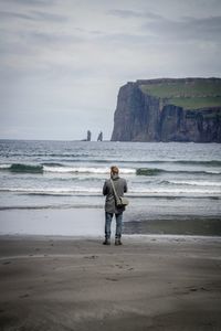 Rear view of man standing on beach against sky
