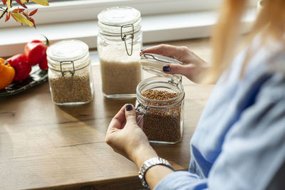 Women opening jar with seeds in kitchen