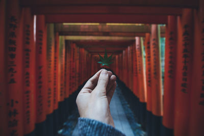 Midsection of person holding cross in temple