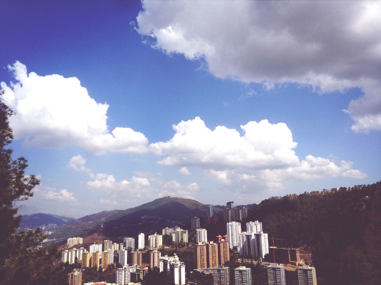 building exterior, architecture, built structure, sky, mountain, cloud - sky, cityscape, city, mountain range, cloud, cloudy, residential district, residential building, residential structure, crowded, town, house, outdoors, day, travel destinations