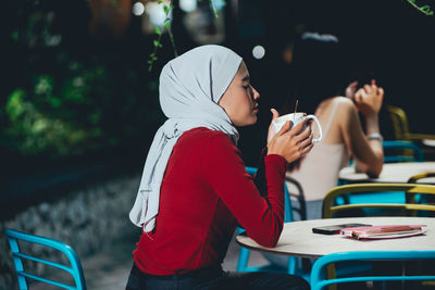 Side view of woman sitting in cafe