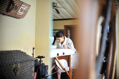 Woman writing while sitting on table at home