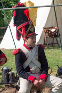 Midsection of man holding red while sitting outdoors