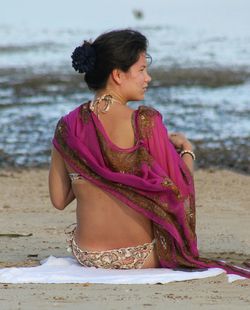 Rear view of woman sitting on beach