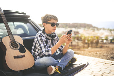 Boy using phone while sitting in car