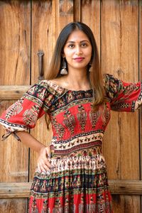 Portrait of smiling young woman standing against wooden door