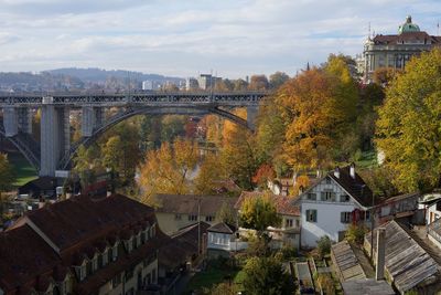 Arch bridge over river amidst buildings in city against sky