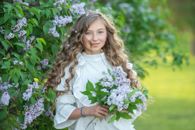 Portrait of a smiling young woman standing against plants