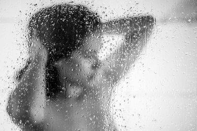 Full length of woman seen through wet glass window